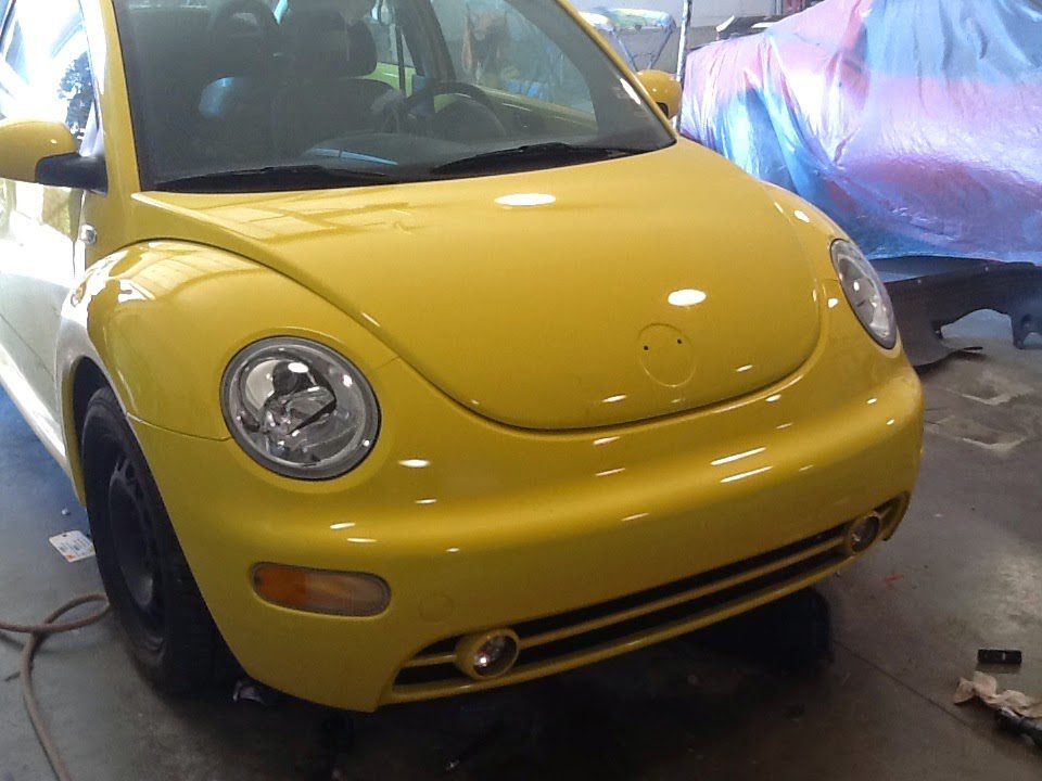 Yellow Volkswagen Beetle undergoing collision repair at Lyle's Collision auto body shop.
